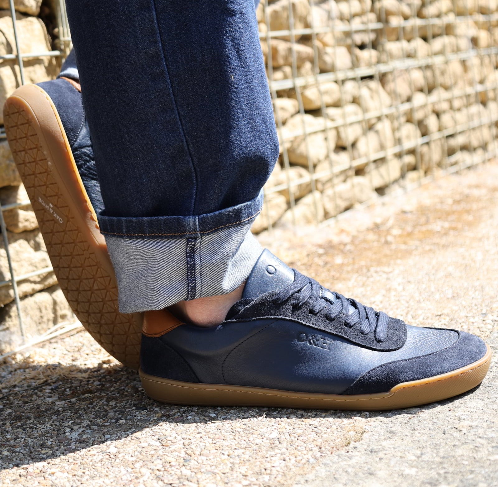 model wearing dark blue aspen trainers leaning against a wall oudoors