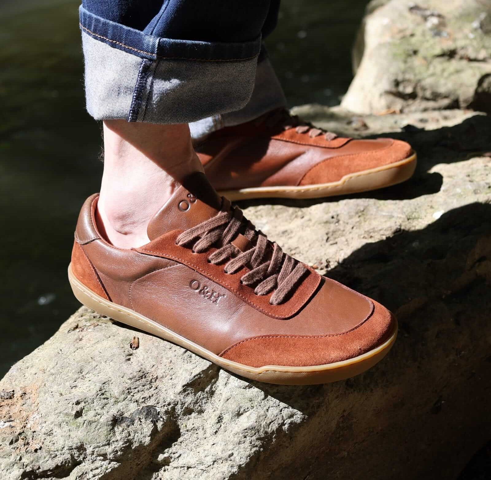 model standing on a rock in aspen barefoot trainers with blue jeans on