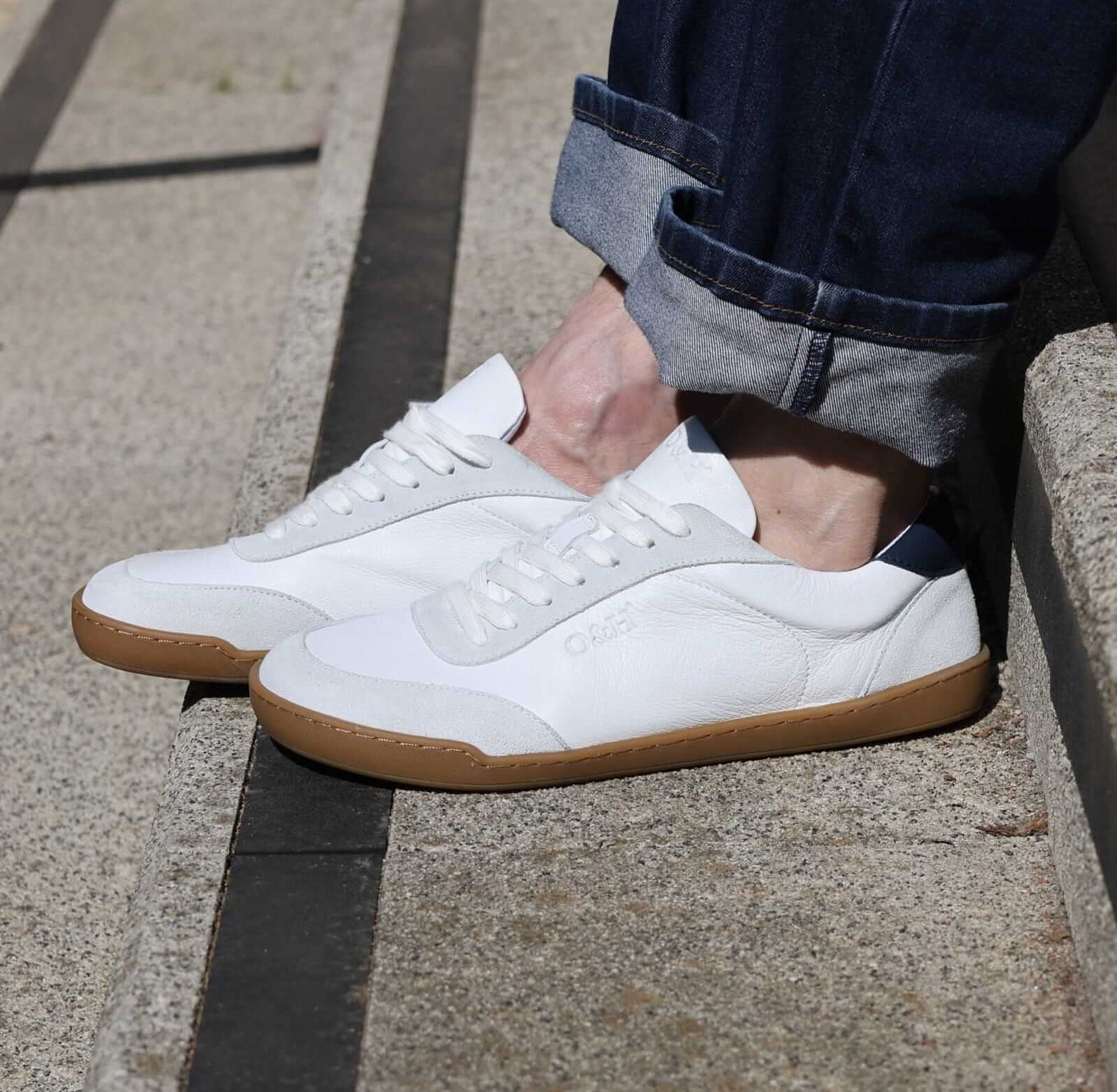 model sitting on concrete steps showing side view of white aspen barefoot trainers