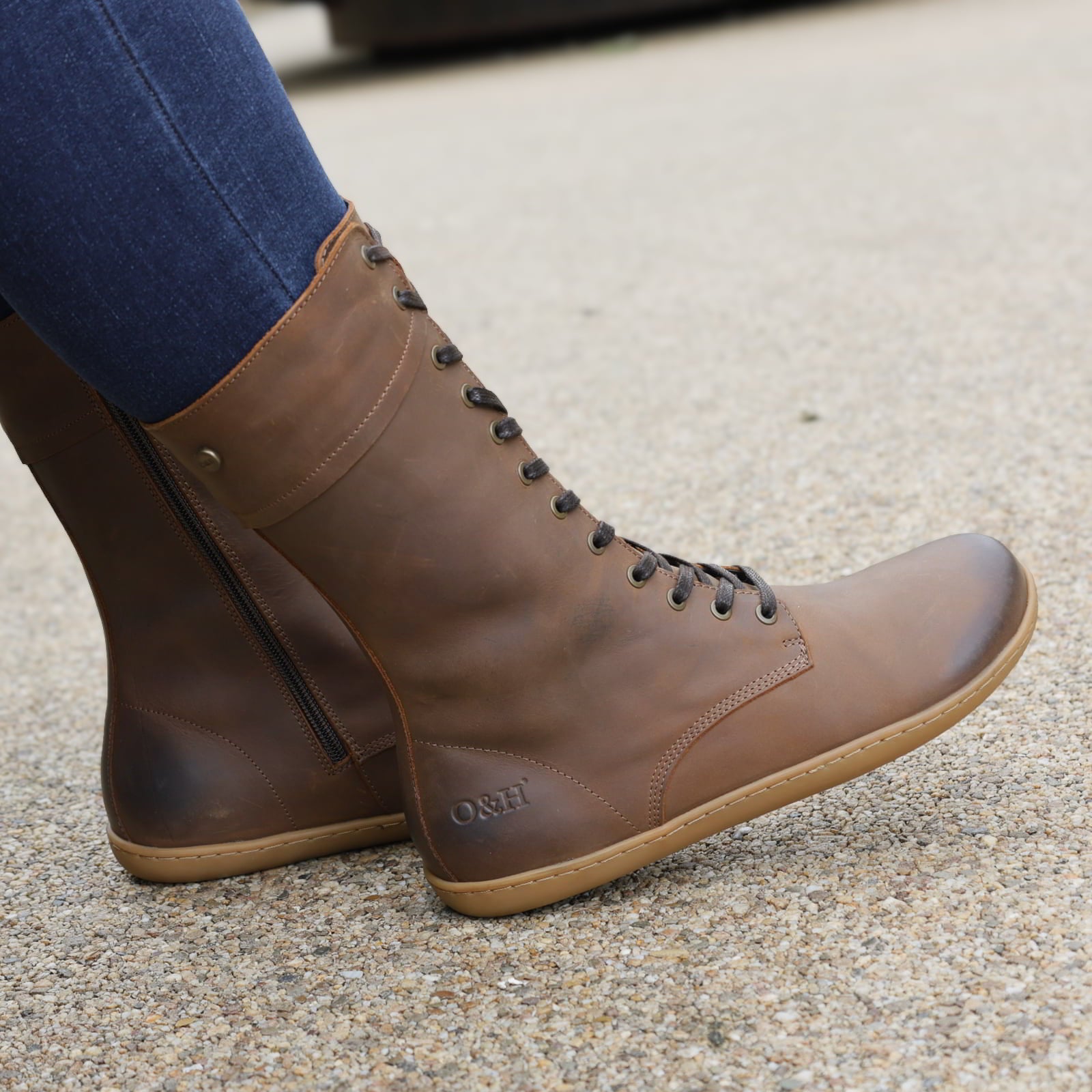 model sitting outdoors wearing beech 12 brown barefoot boots with blue jeans