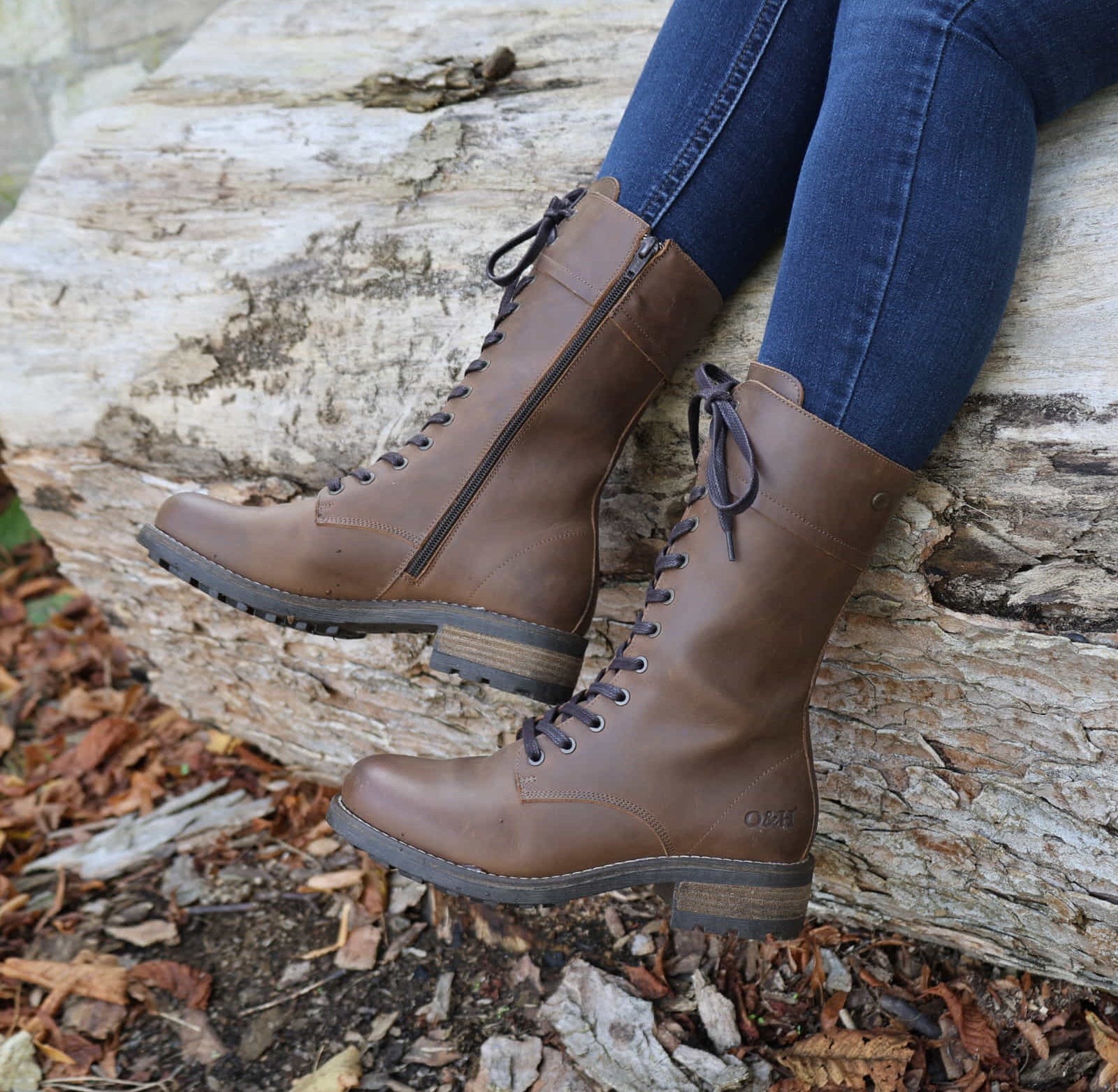 Dark brown Bridge 12 military boots worn outdoors while seated on a stone surface