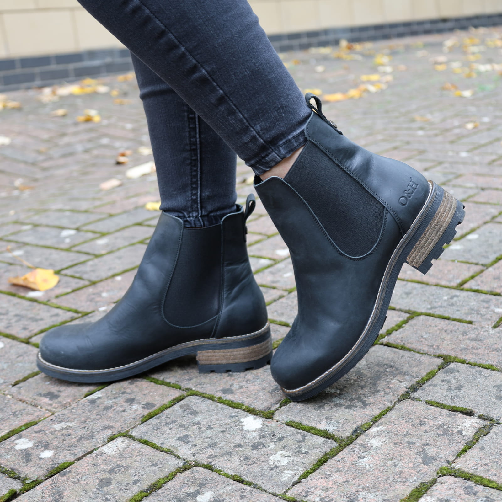 model wearig black bridge chelsea boots with dark jeans on pavement
