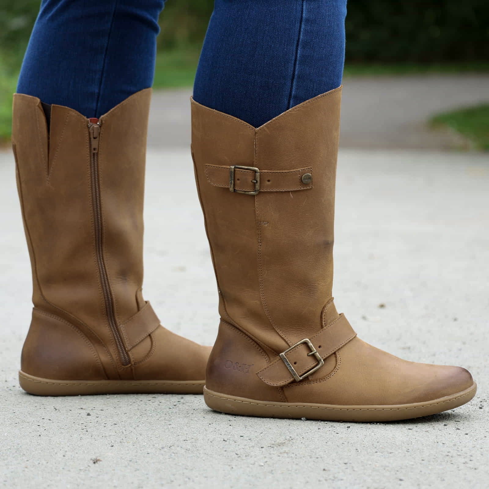 person standing on path in tan barefoot boots with blue jeans