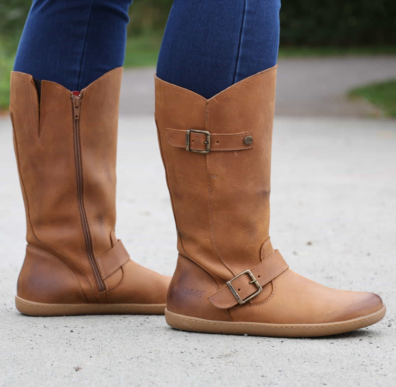 person standing on path in tan barefoot boots with blue jeans