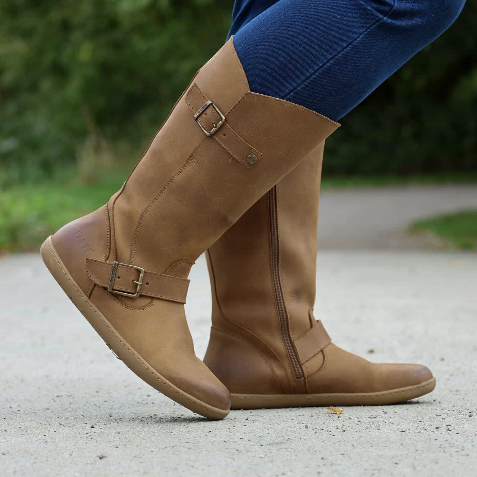 person wearing tan boots with blue jeans on outdoor path