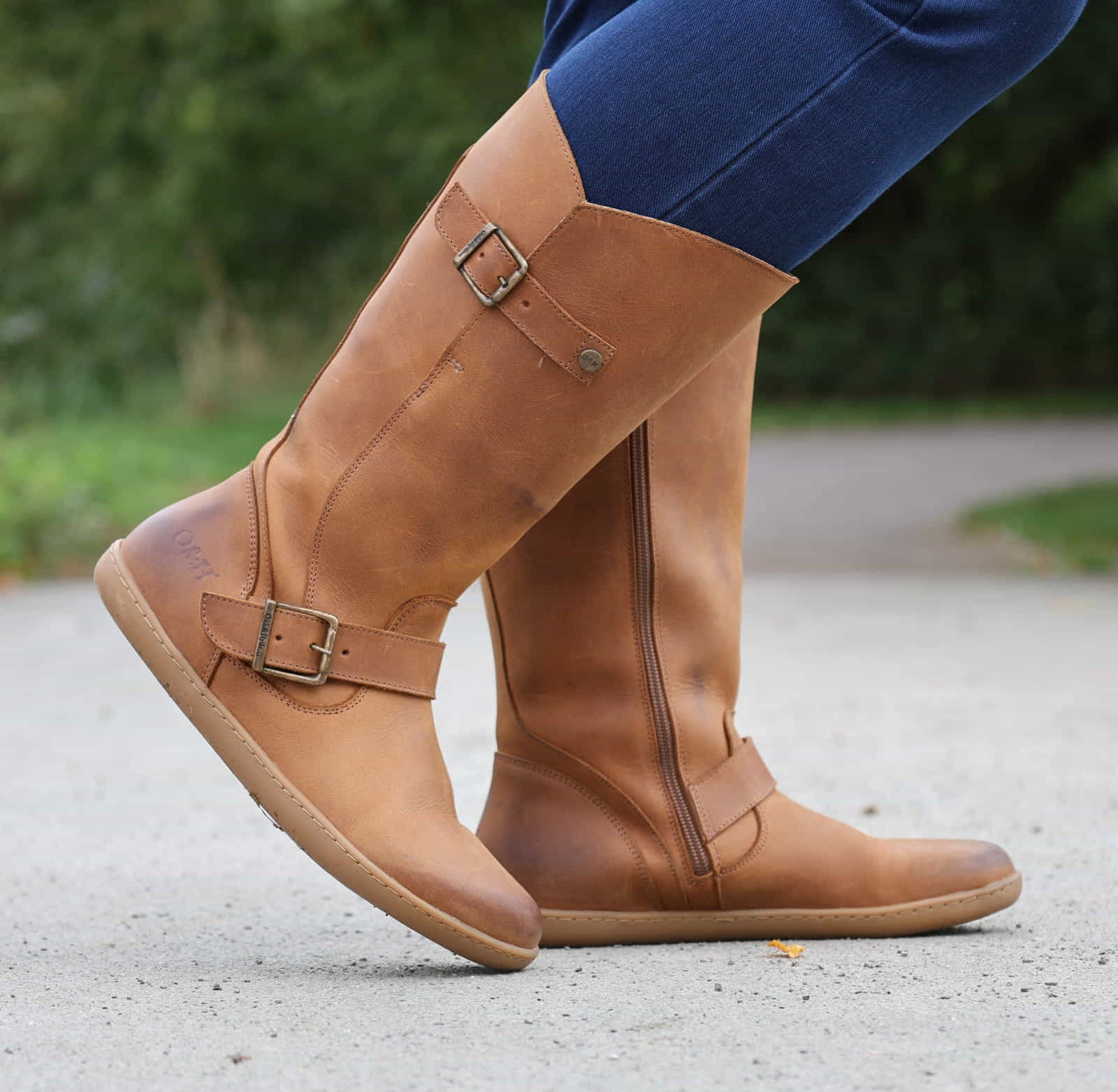 person wearing tan boots with blue jeans on outdoor path