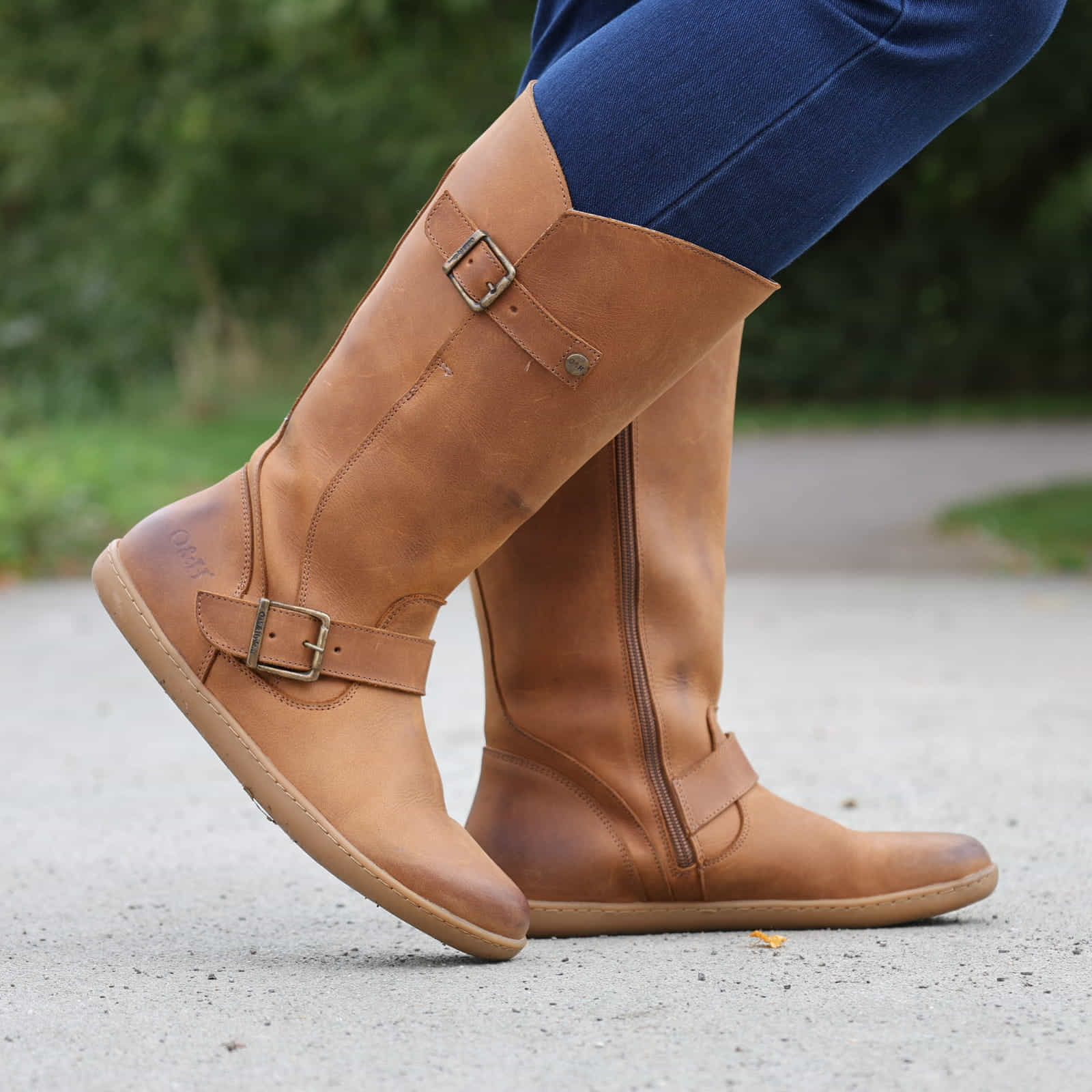 person wearing tan boots with blue jeans on outdoor path