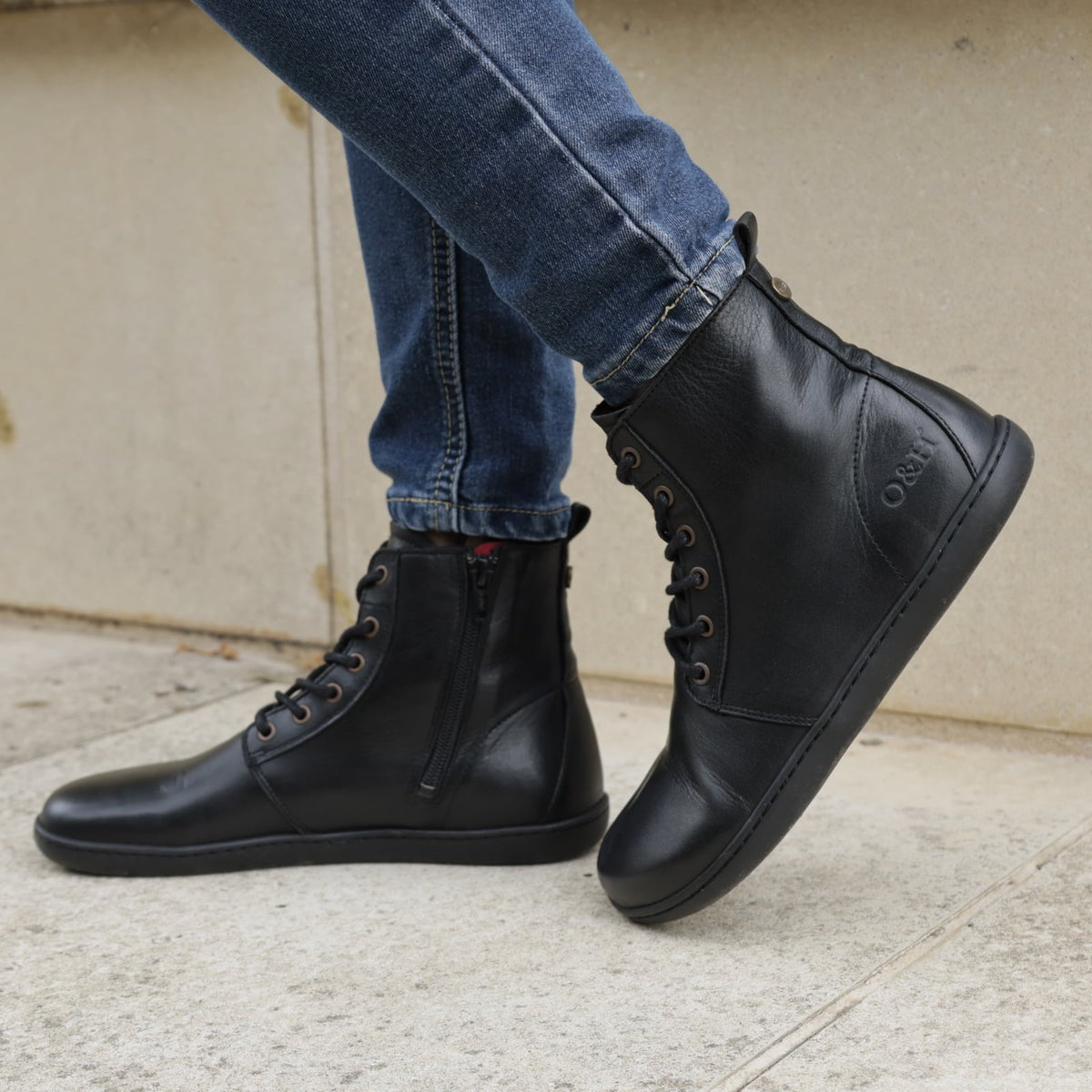 model standing outdoors on pavement wearing the womens cherry barefoot ankle boots in black