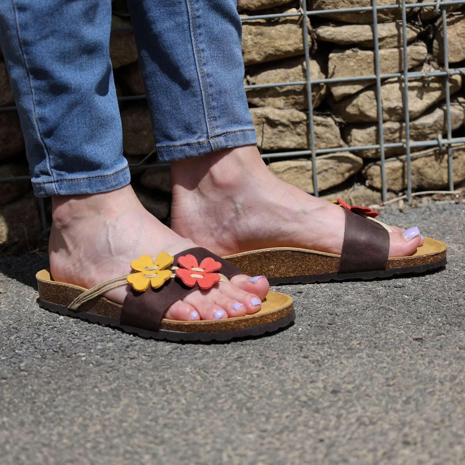 model wearing clover sandals in dark brown with blue skinny jeans outdoors