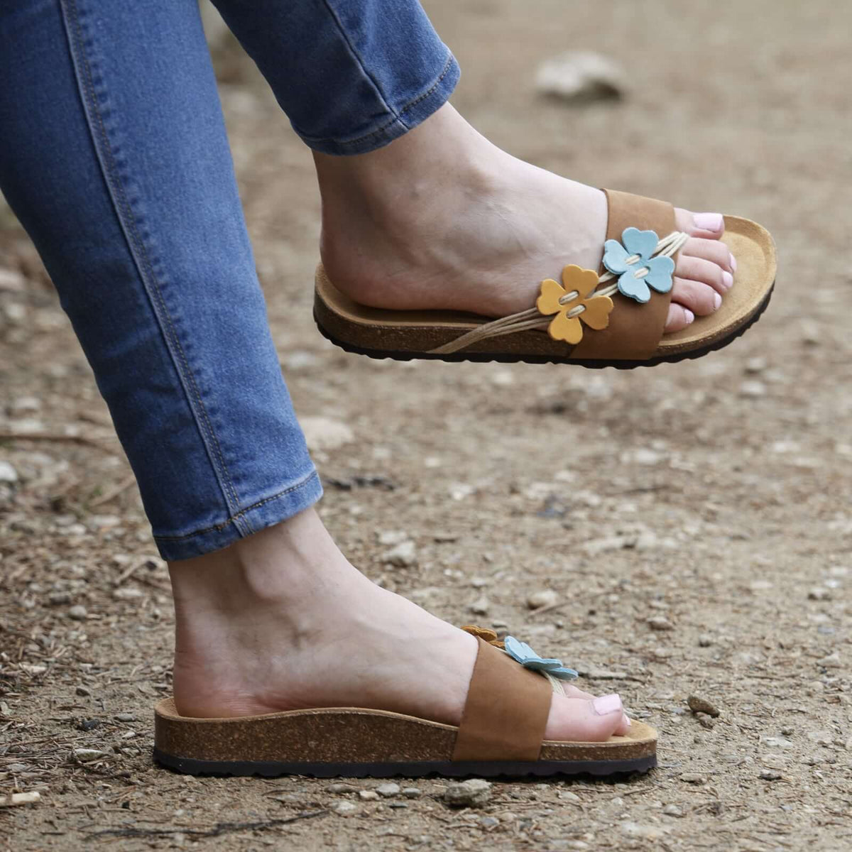 model wearing clover sandals in tan with blue jeans sitting outside
