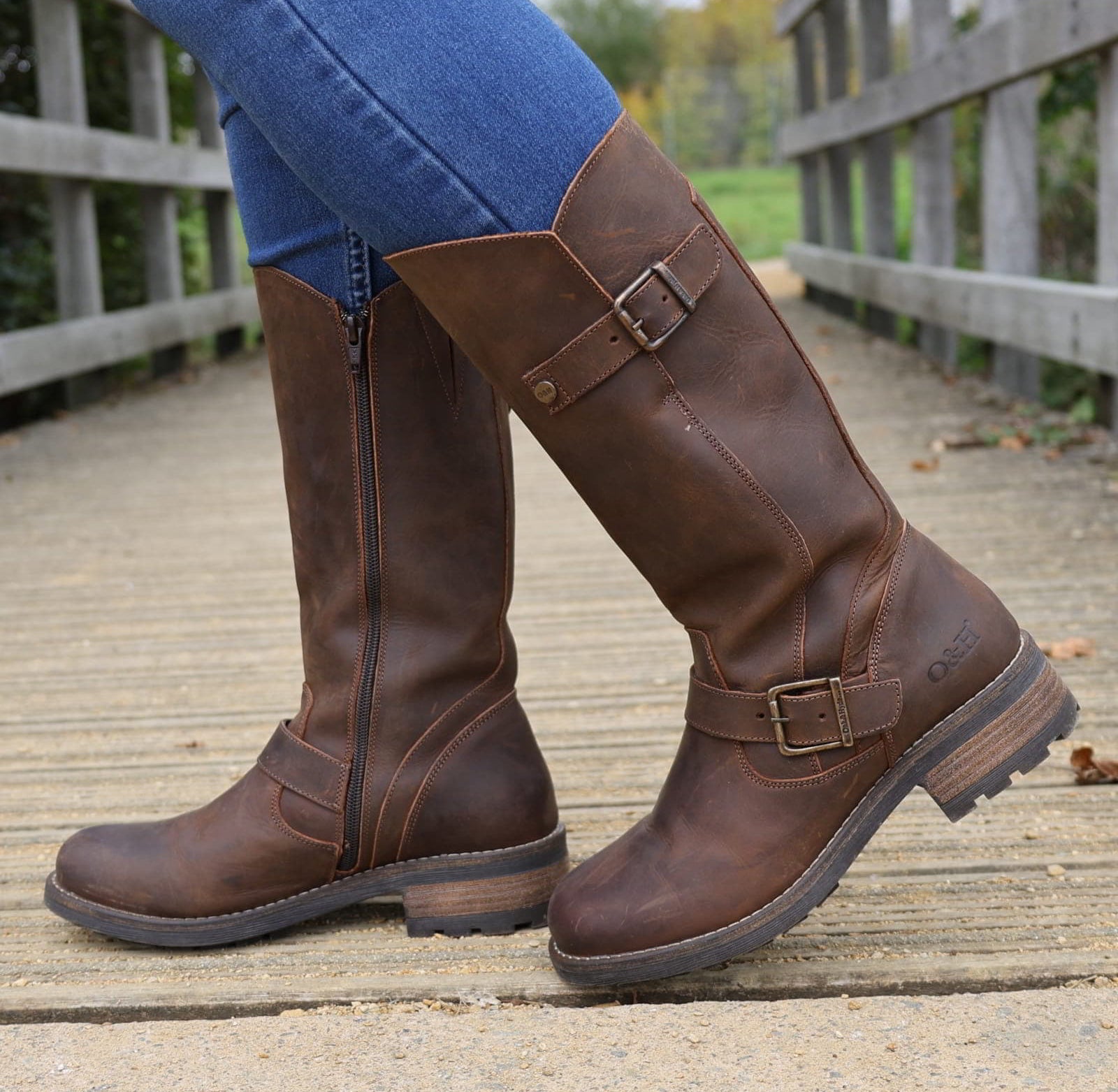 Dark brown Crest 2 tall boots worn with jeans walking on a wooden footbridge