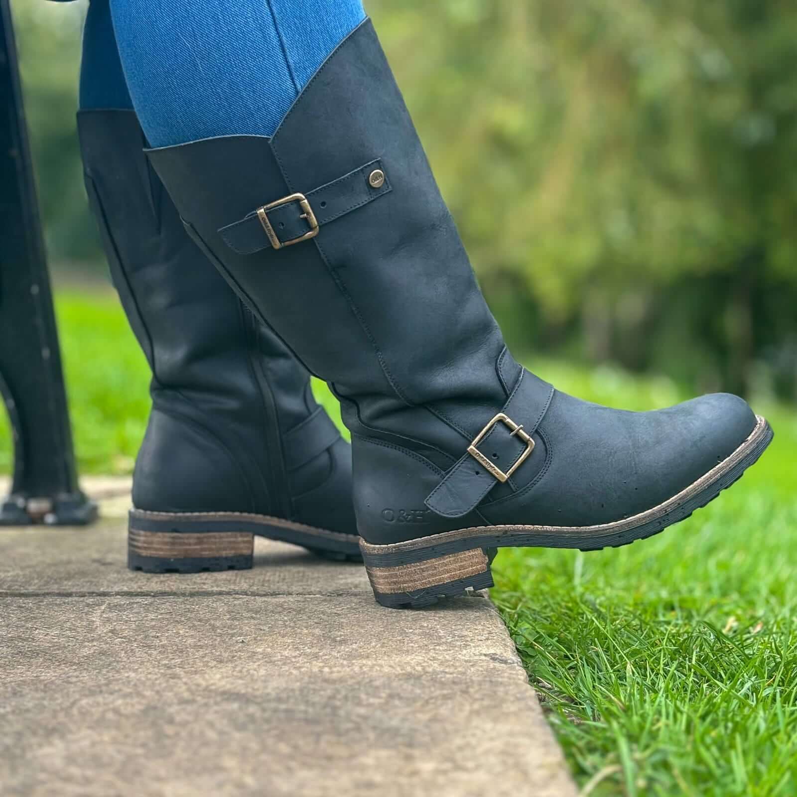 Black Crest 2 wide calf tall boots worn outdoors sitting on a bench