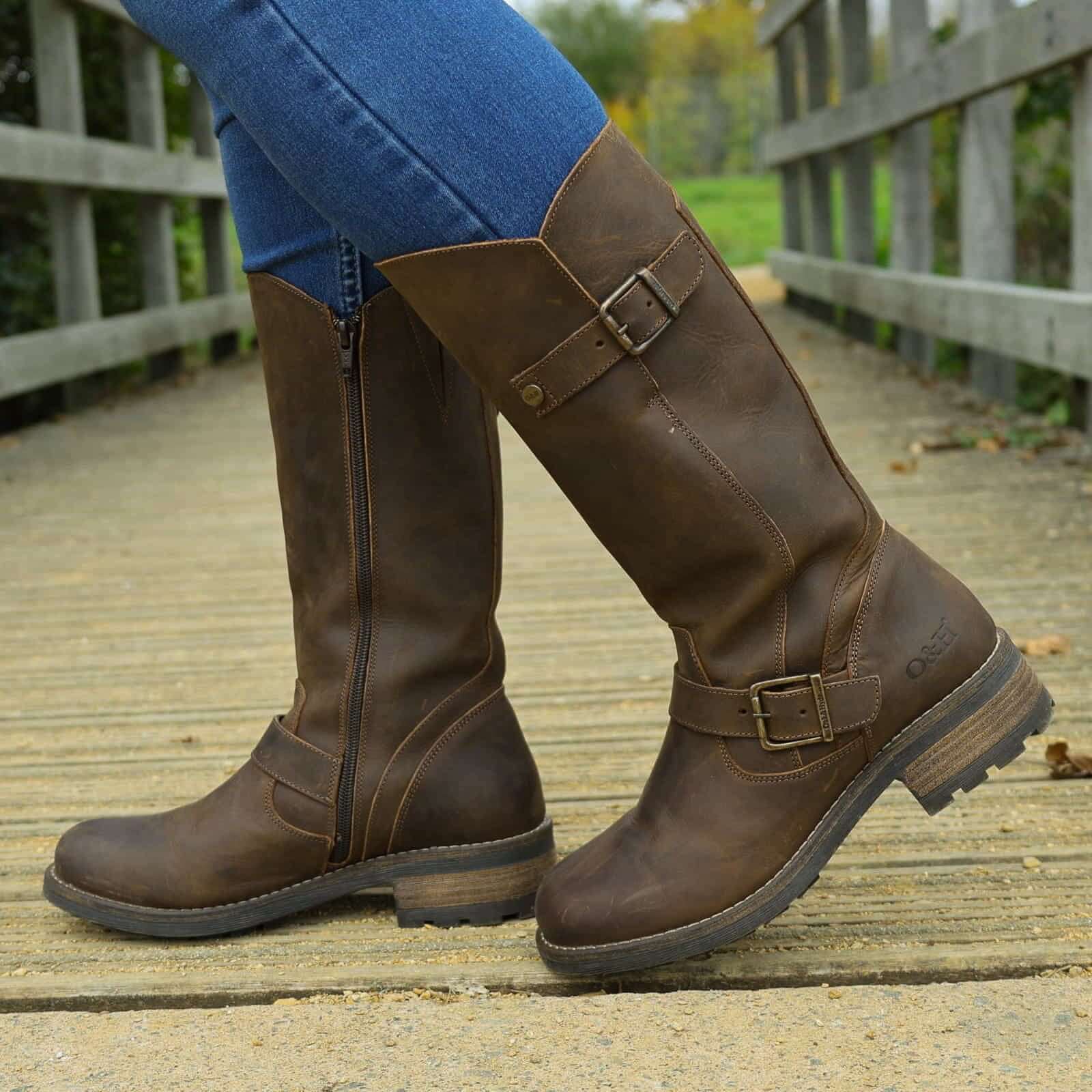 Dark brown Crest 2 tall boots worn with jeans walking on a wooden footbridge