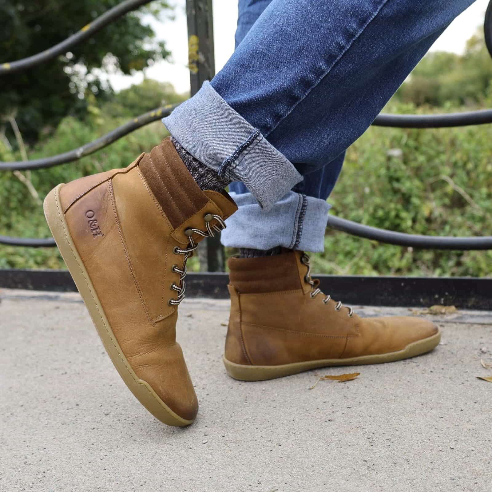 person wearing tan hawthorn barefoot boots with jeans stood on a bridge
