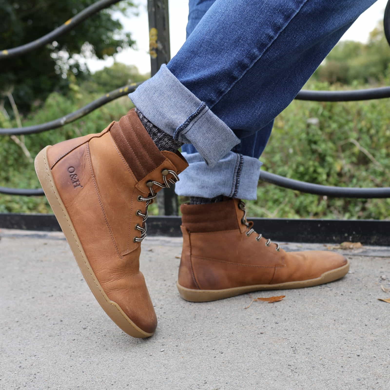 person wearing tan hawthorn barefoot boots with jeans stood on a bridge