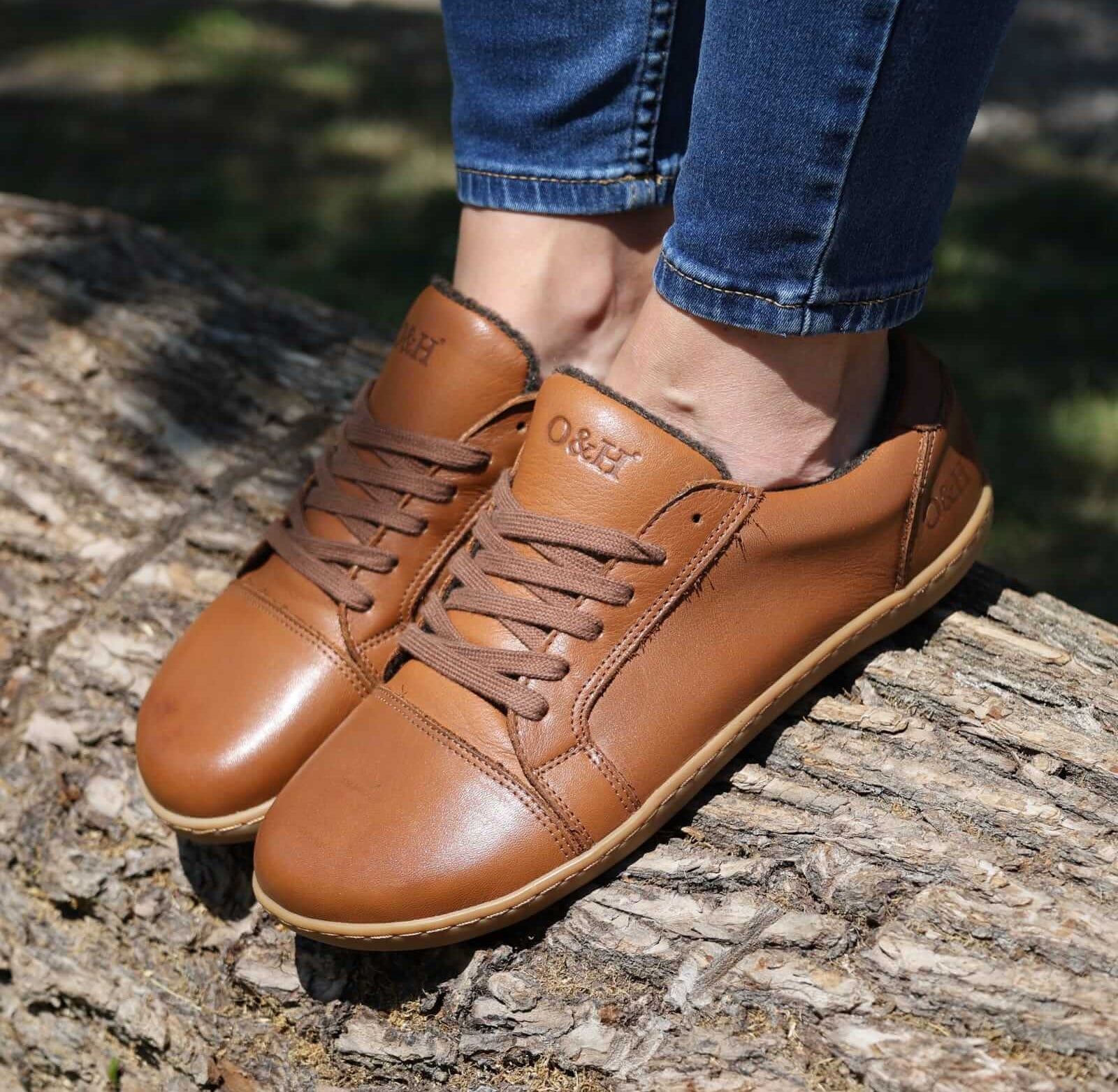 model wearing tan brown barefoot trainers stood on a log with jeans on