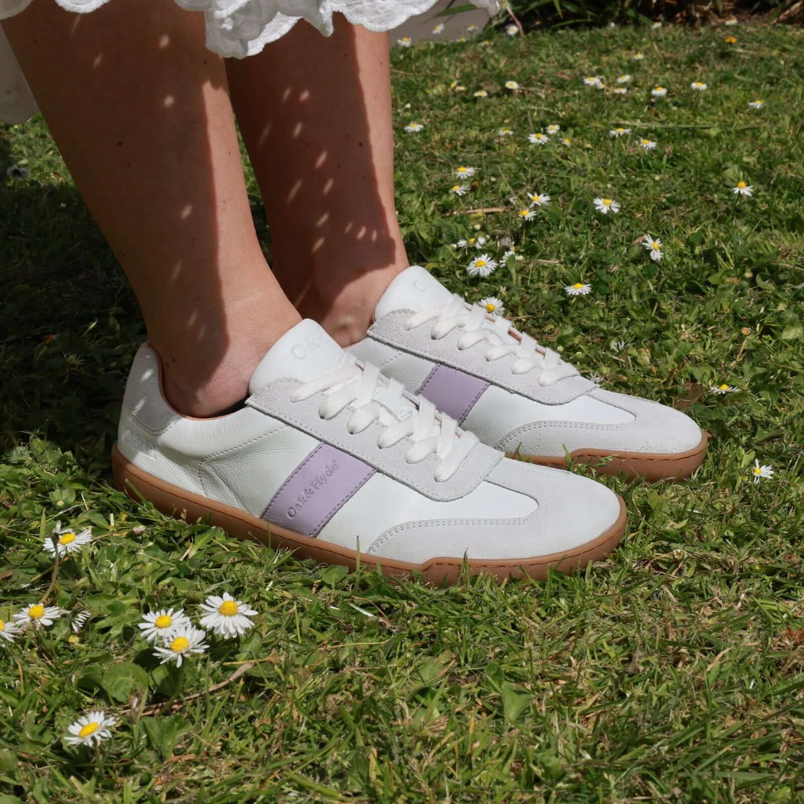 person wearing white lilac juniper trainers standing on grass