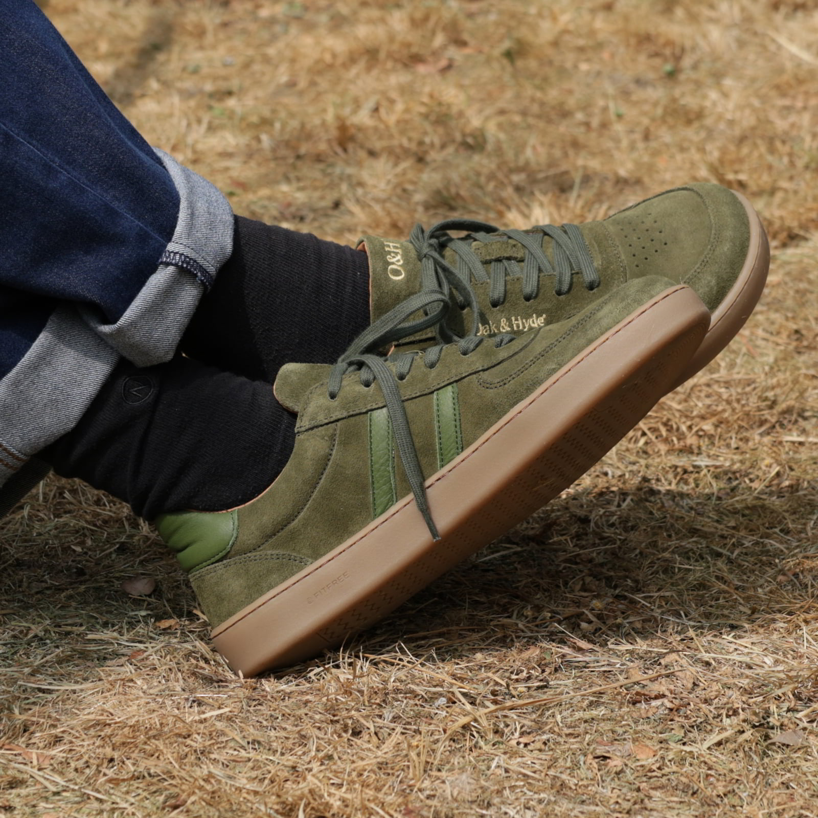 person wearing mens larch barefoot trainers in green sitting outdoors