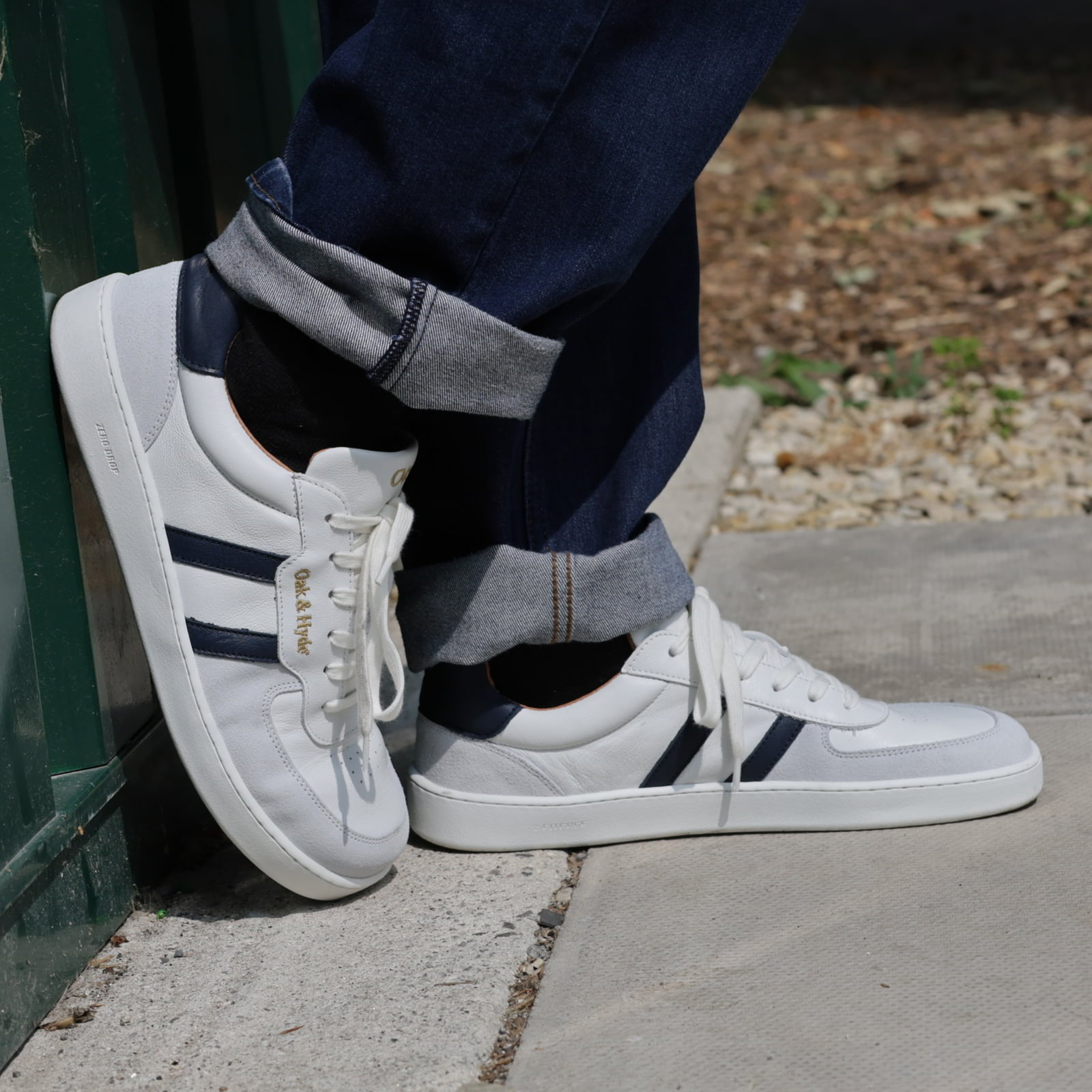 model standing outdoors wearing mens larch barefoot trainers in white navy