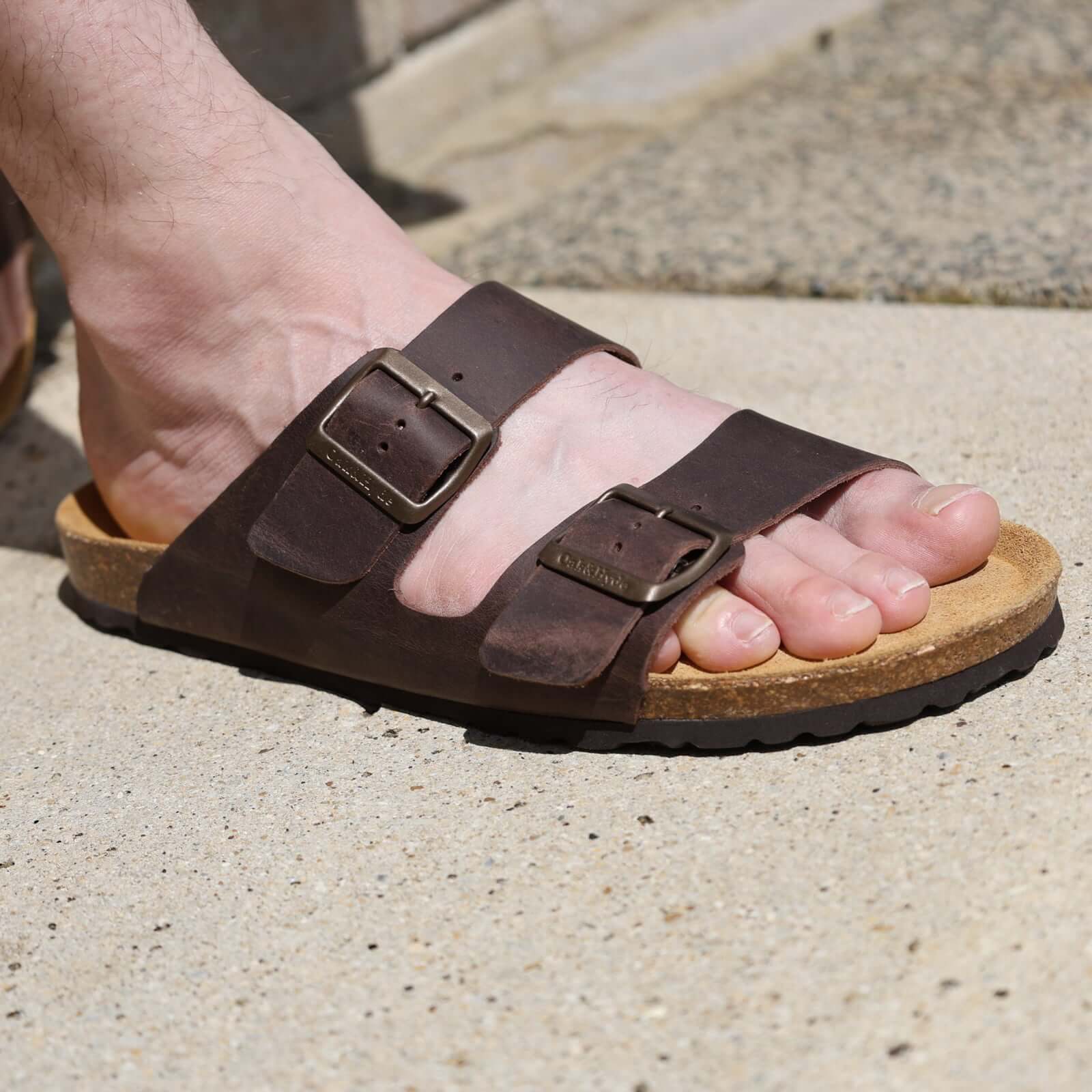 dark brown oak & hyde malaga sandals worn outdoors showing open toe straps and cork footbed