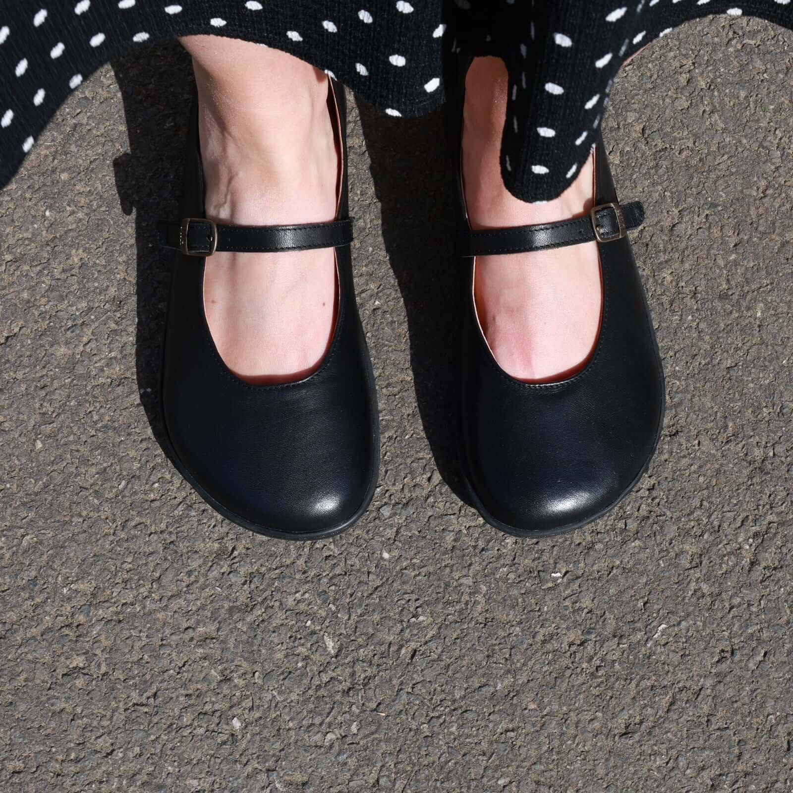 person wearing olive barefoot mary jane shoes in black showing a top down view of the toe box shape