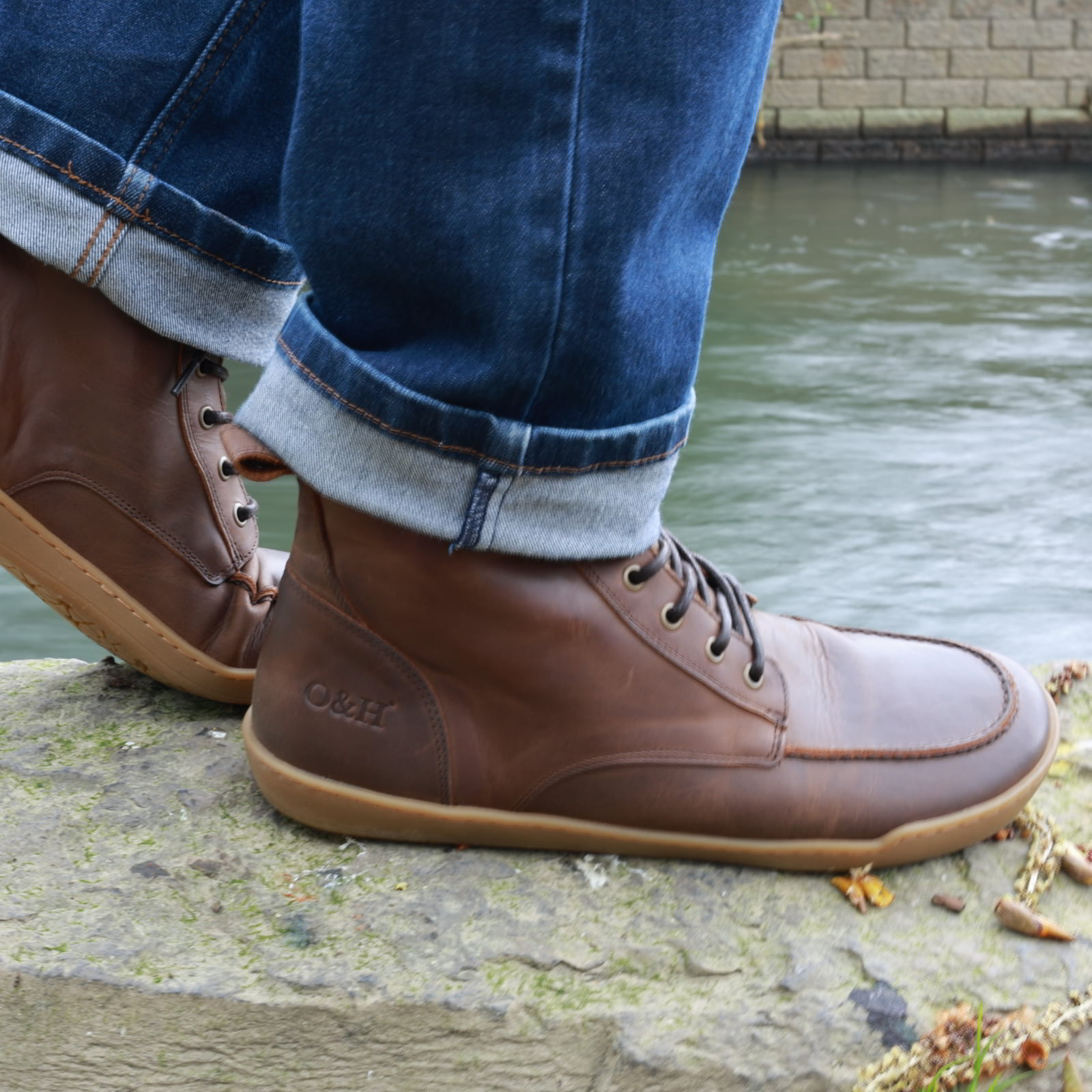 person wearing redwood barefoot boots in dark brown in outside setting with jeans