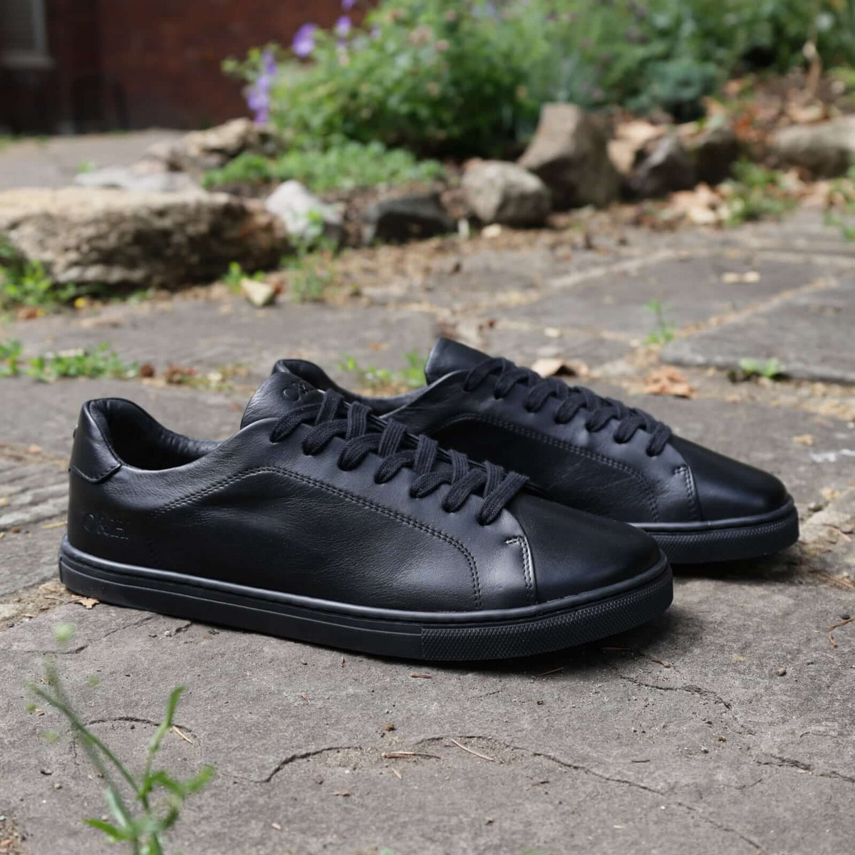 pair of mens all black barefoot shoes outdoors on a pavement