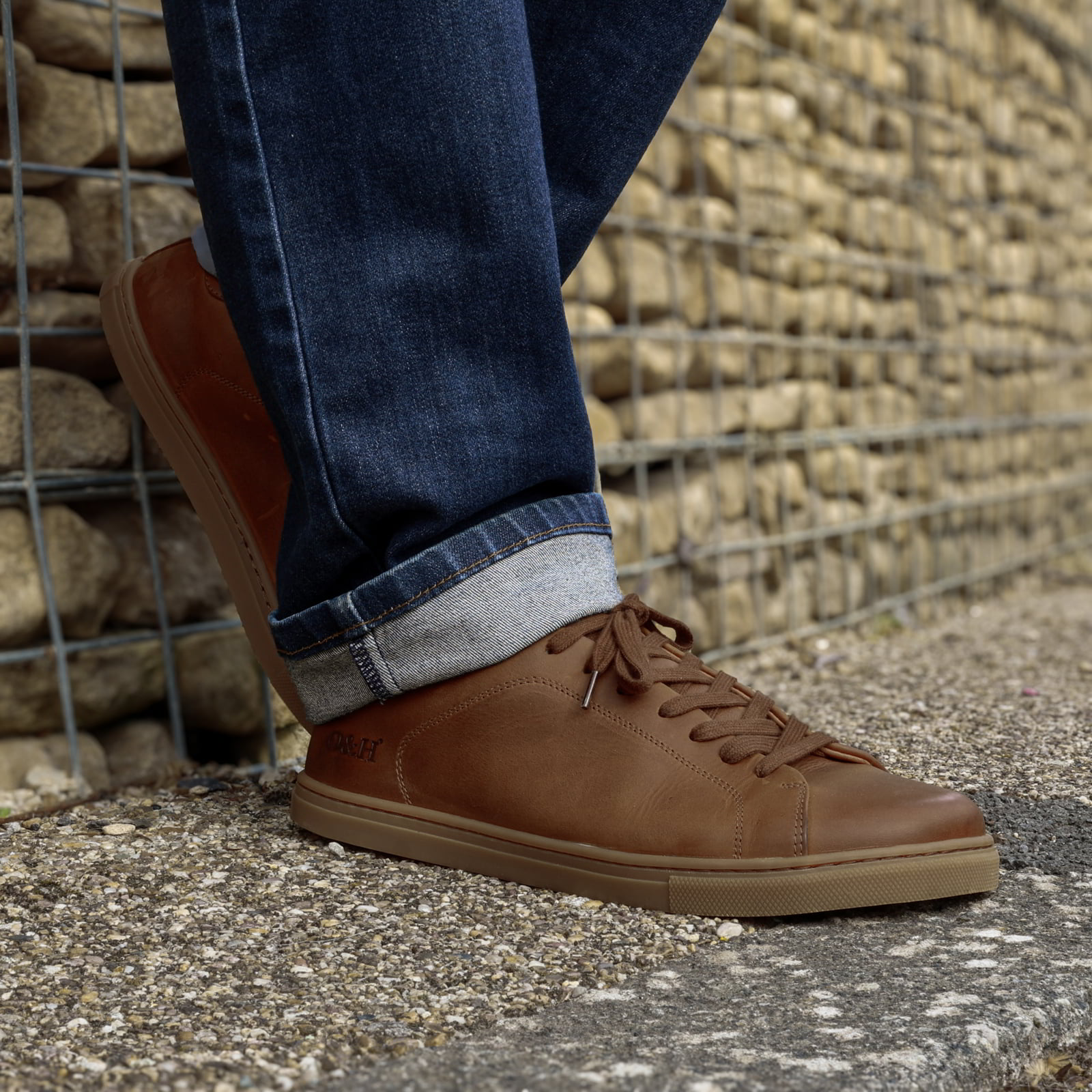 model wearing rowan cognac barefoot shoes with blue jeans leaning against a wall