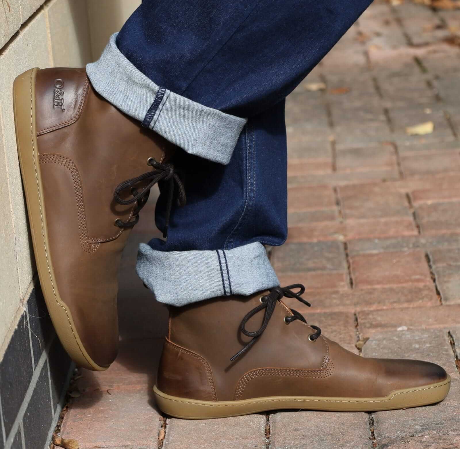 model wearing spruce barefoot boots with blue jeans leaning against a wall