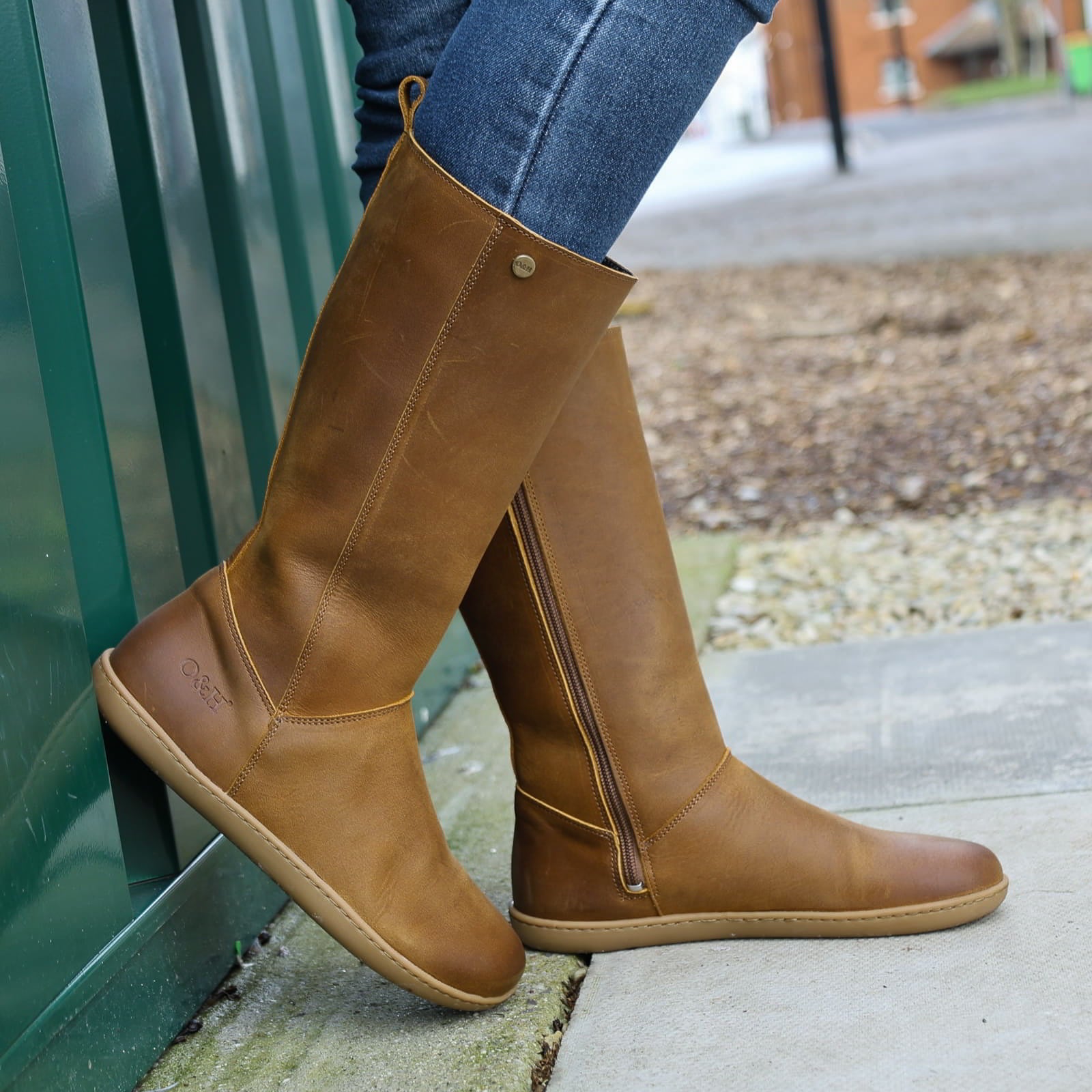 model wearing mid calf tan barefoot boots with blue jeans on concrete floor