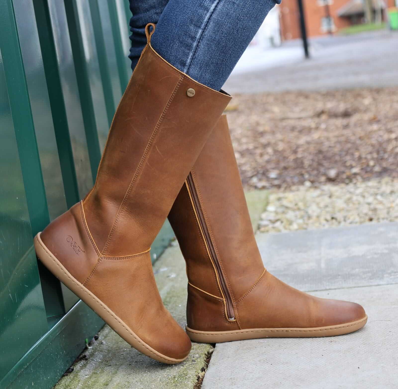 model wearing mid calf tan barefoot boots with blue jeans on concrete floor