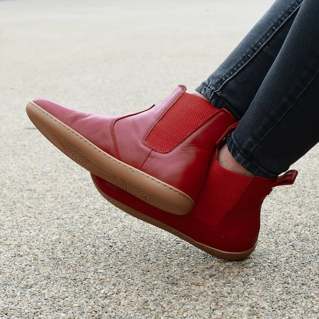 model wearing willow 2 barefoot chelsea boots in red sitting on a bench