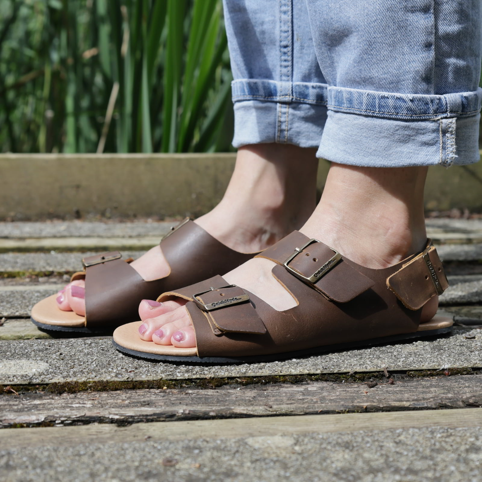 model wearing wisteria barefoot sandals in brown with blue crop jeans standing outdoors