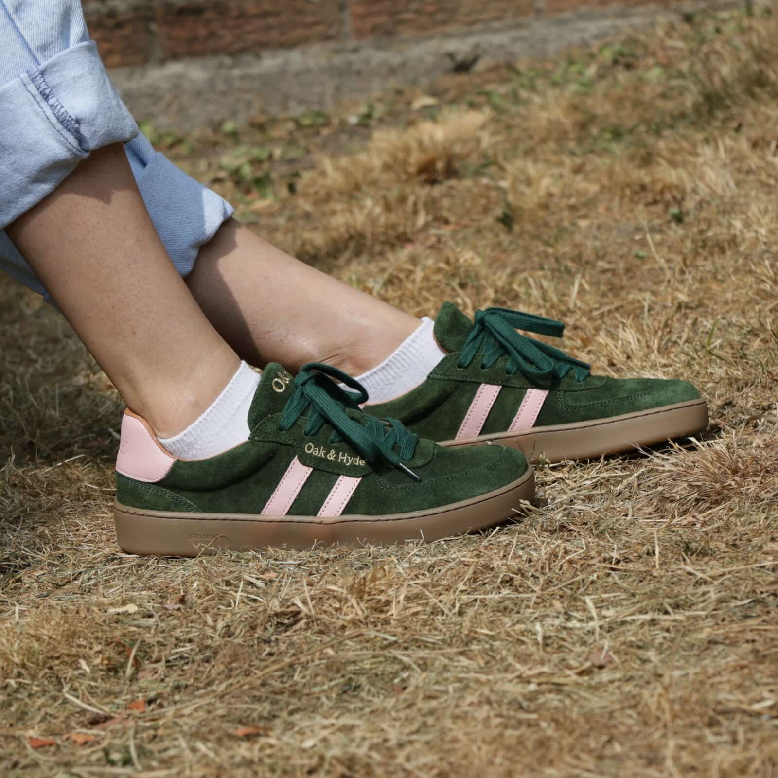 model wearing womens larch barefoot trainers in green pink sitting outdoors