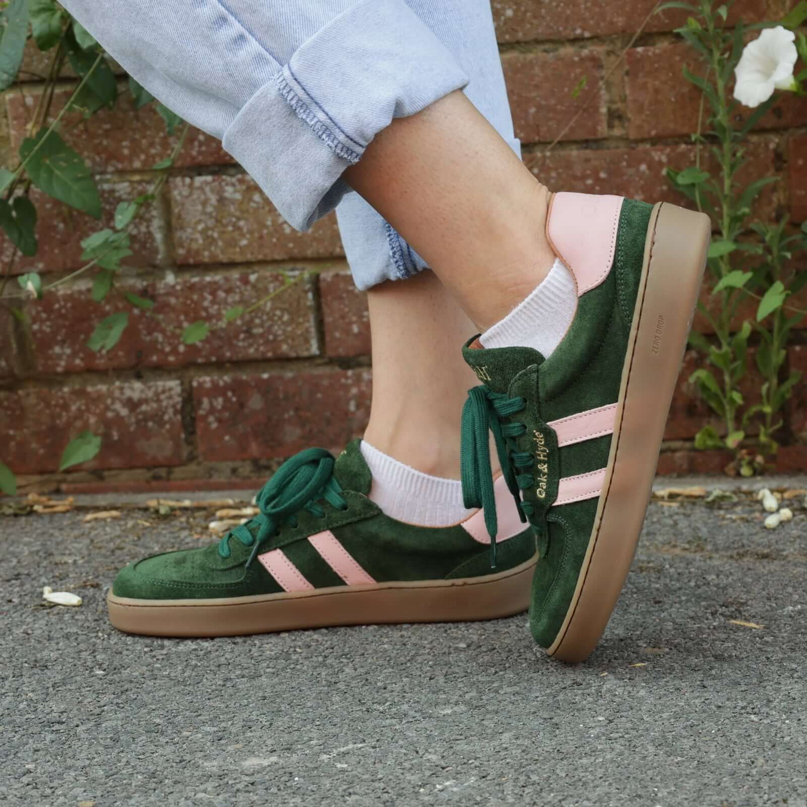 model standing outdoors wearing womens larch barefoot trainers in green pink with blue jeans