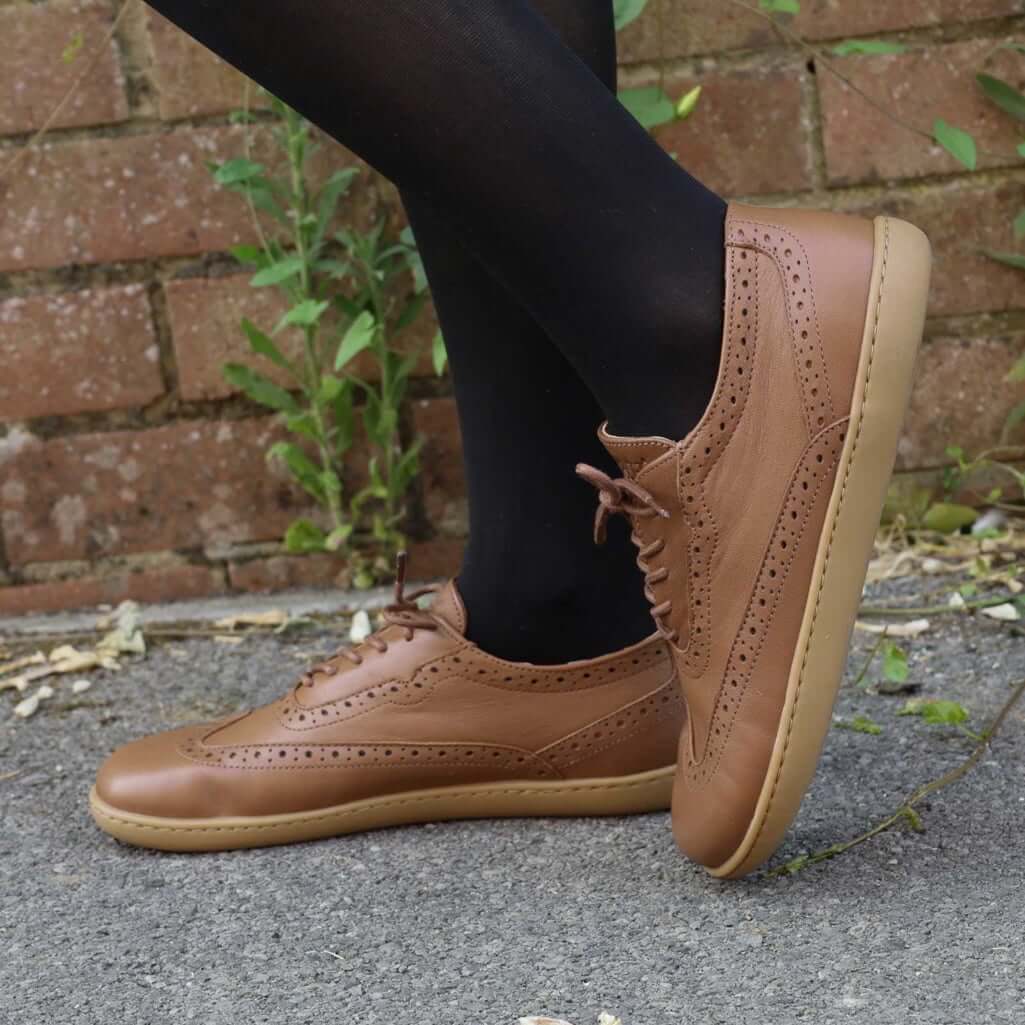 model standing outdoors wearing maple barefoot brogue shoes with black tights