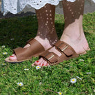 model wearing acacia womens leather barefoot sandals in tan standing on grass