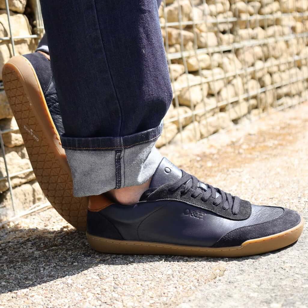 model wearing dark blue aspen trainers leaning against a wall oudoors