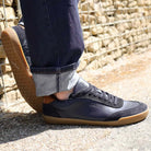 model wearing dark blue aspen trainers leaning against a wall oudoors