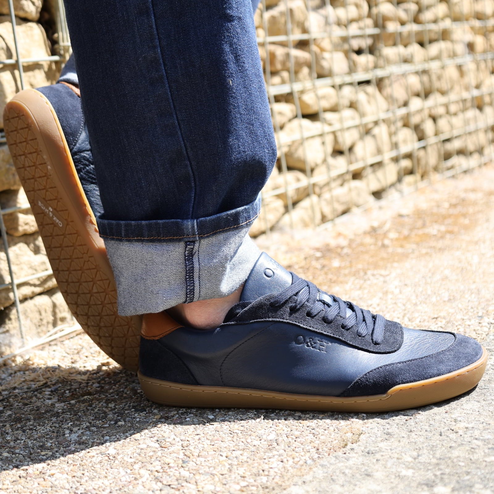 model wearing dark blue aspen trainers leaning against a wall oudoors