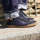person wearing dark blue aspen barefoot trainers on concrete pavement with blue jeans