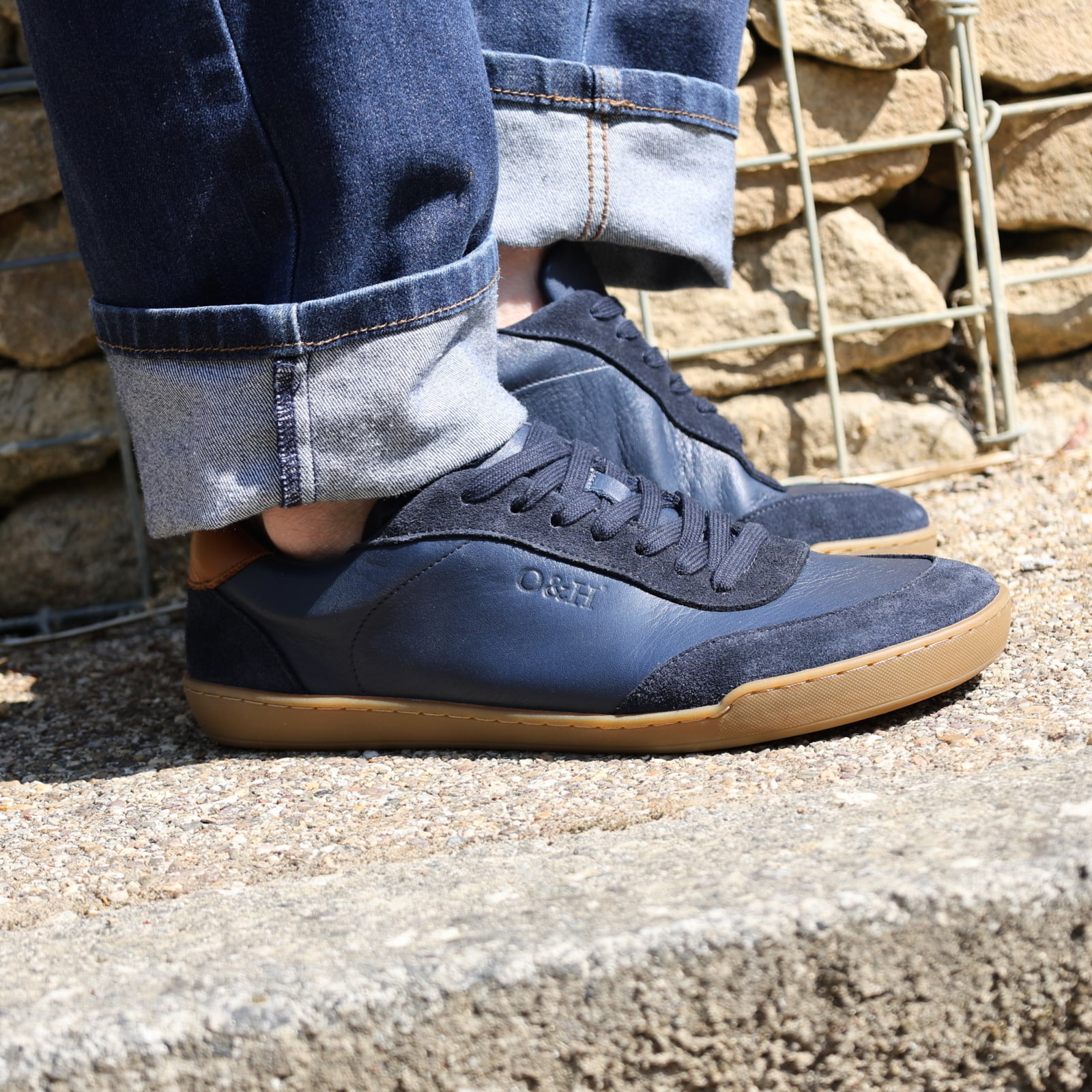 person wearing dark blue aspen barefoot trainers on concrete pavement with blue jeans