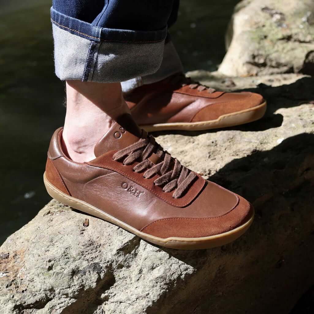 model standing on a rock in aspen barefoot trainers with blue jeans on
