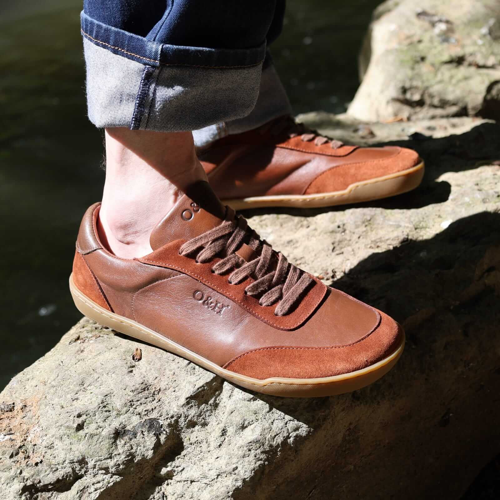 model standing on a rock in aspen barefoot trainers with blue jeans on