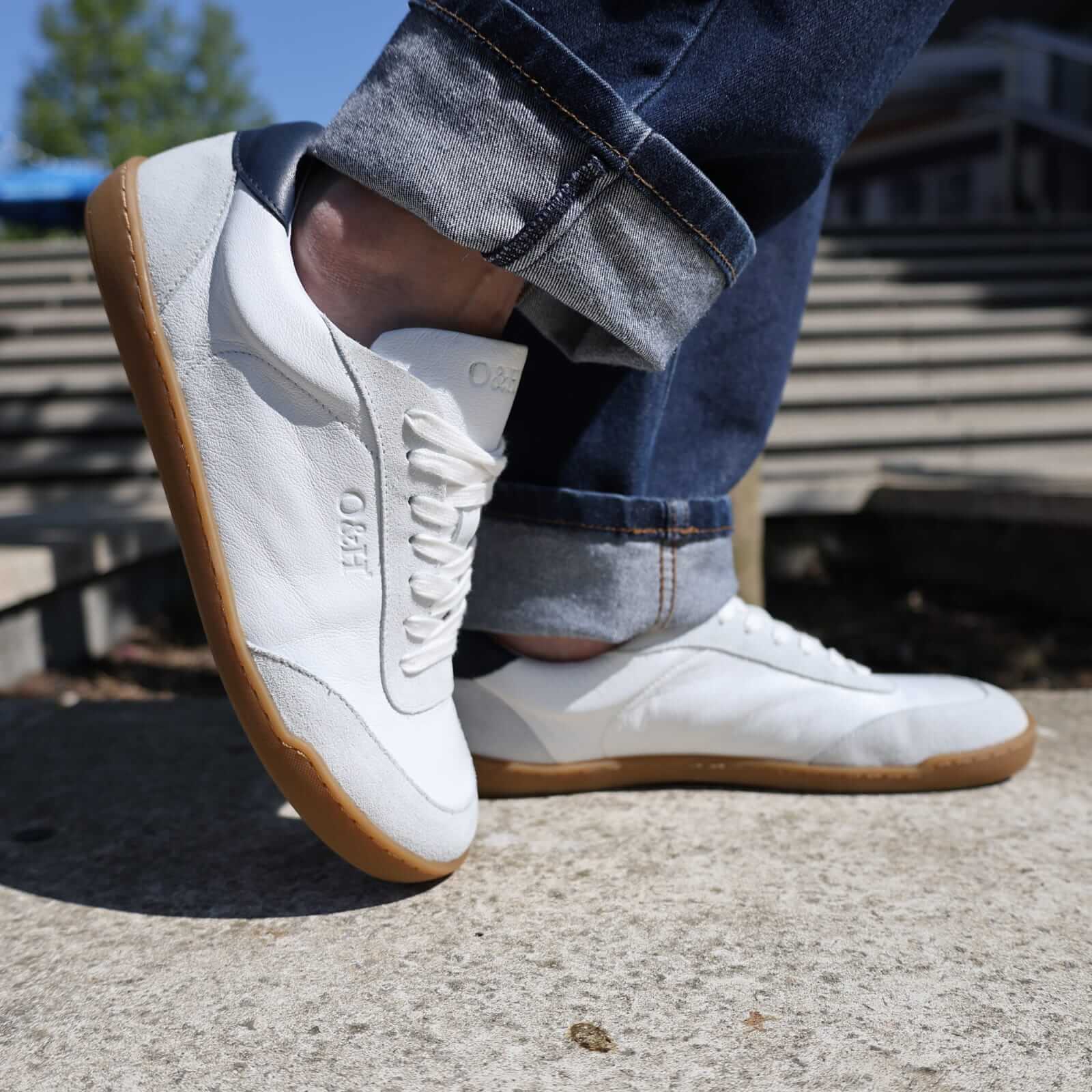 model standing on concrete pavement wearing white aspen barefoot trainers with jeans