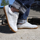 model standing on concrete pavement wearing white aspen barefoot trainers with jeans