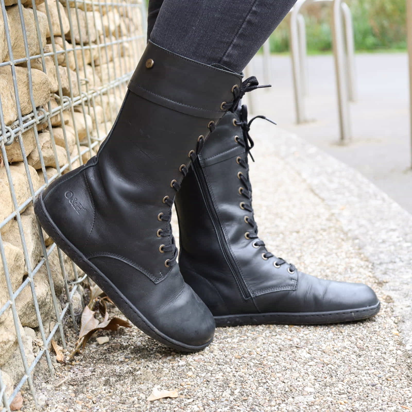 model wearing beech 12 black barefoot boots with dark jeans leaning against a wall