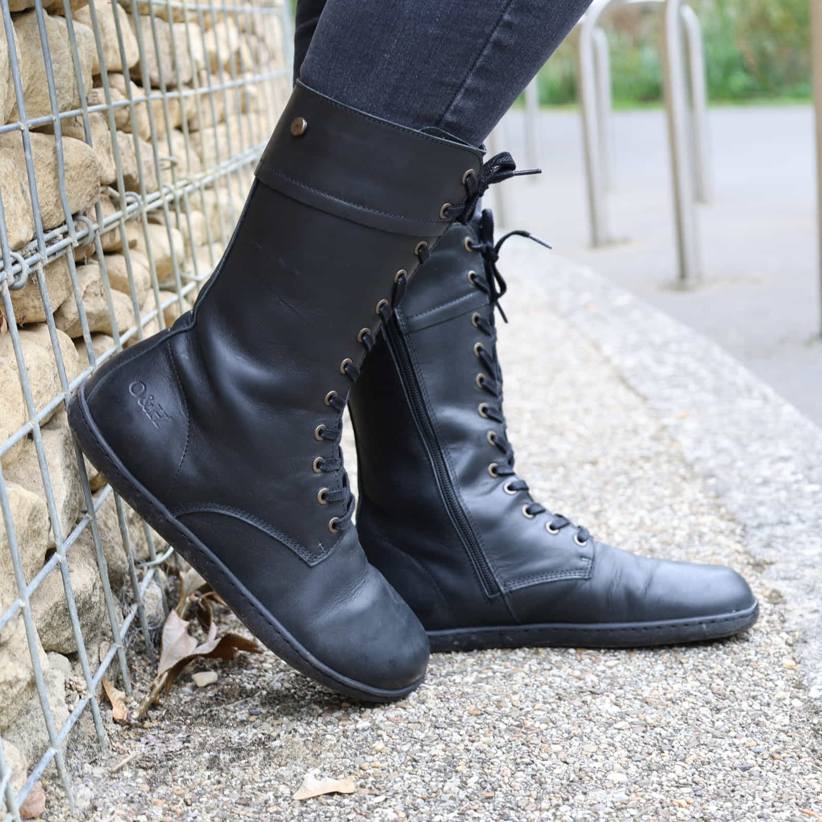 model wearing beech 12 black barefoot boots with dark jeans leaning against a wall