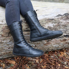 model wearing beech 12 boots in black with jeans sitting on a fallen tree trunk