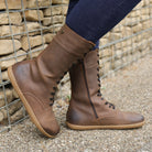 model standing outdoors wearing beech 12 barefoot boots leaning against a wall